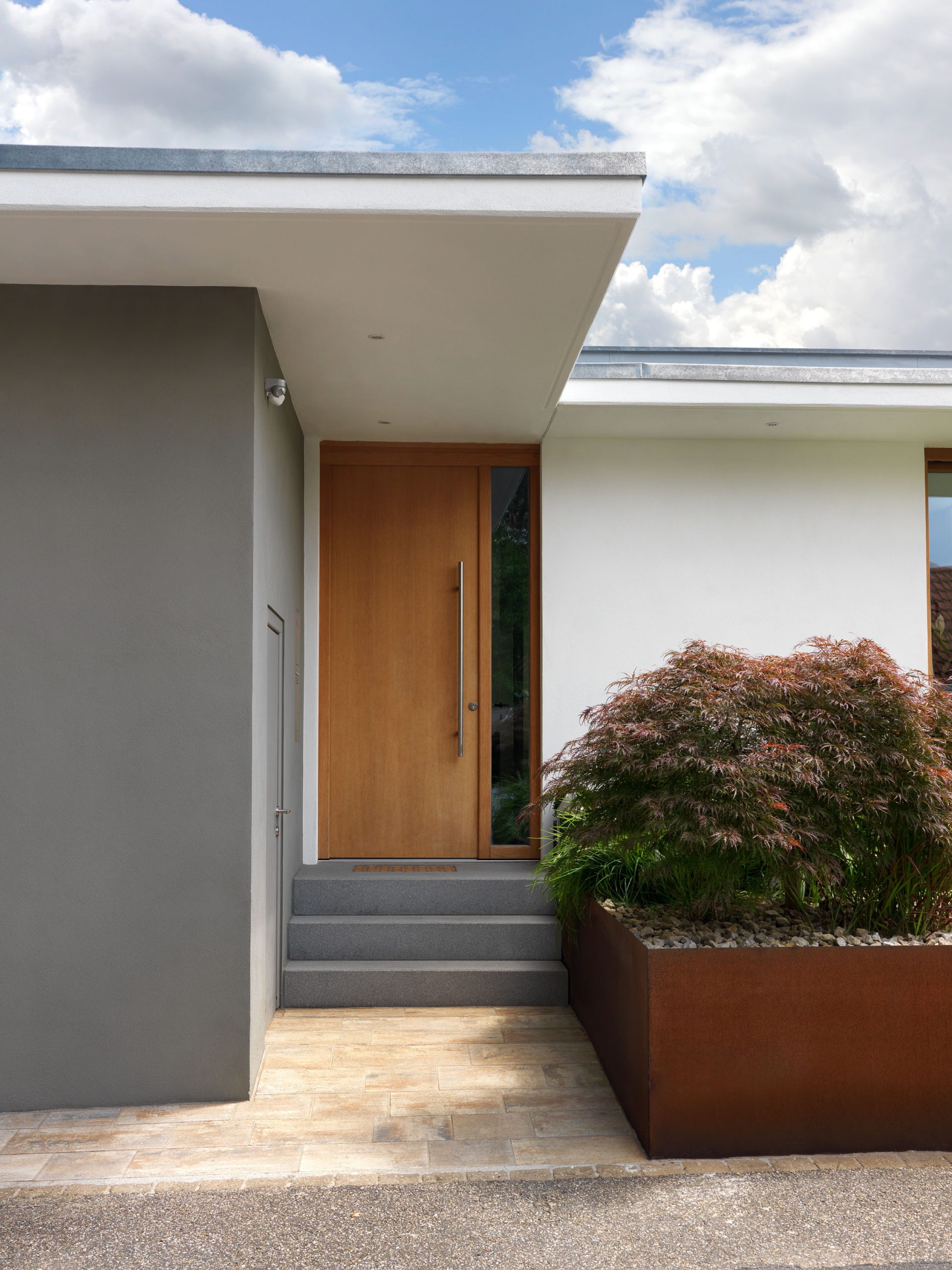 Blick auf den Eingangsbereich des Hauses BRM mit Pflanzkübel aus Cortenstahl.