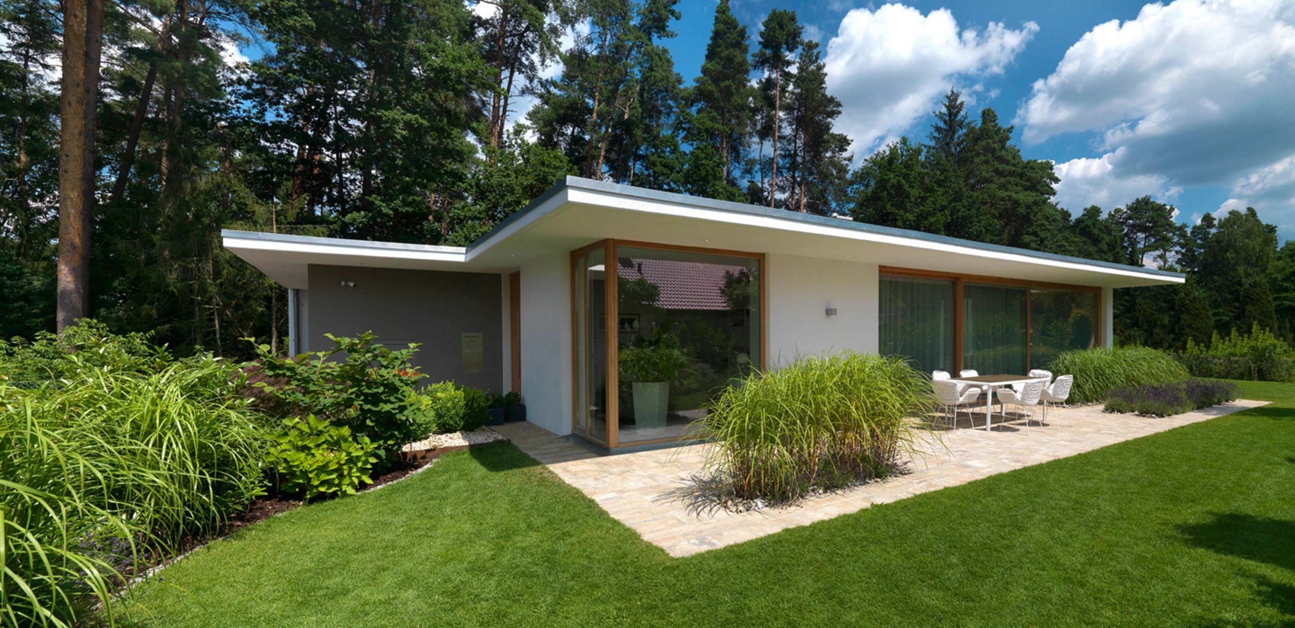 Perspektive aus dem Garten mit Blick auf die Terrasse mit Essbereich von Einfamilienhaus