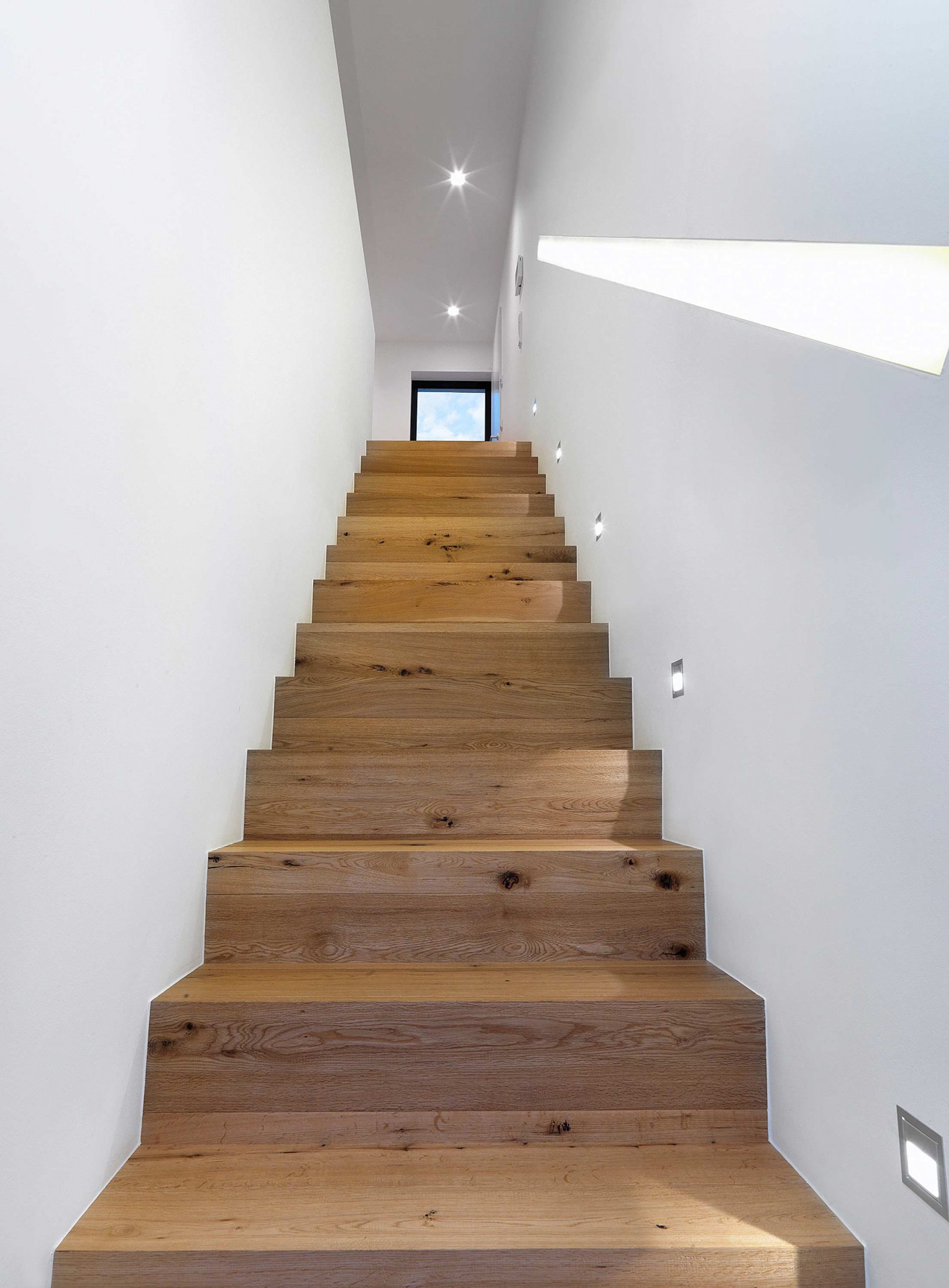Die gerade Treppe mit Echtholzverkleidung und abschnittsweisen LED-Strahlern im Einfamilienhaus 