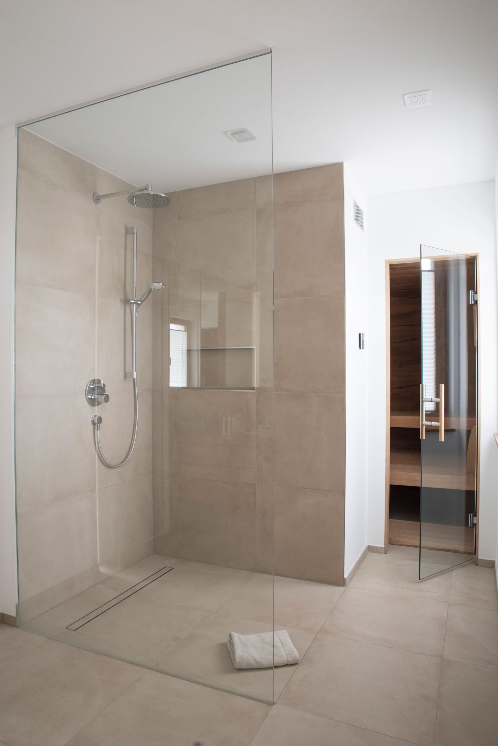 Walk-In Duschbereich im Wellness Bereich des Hauses WEL mit bodengleichem Abflusssystem und runder Regenwald-Brause.