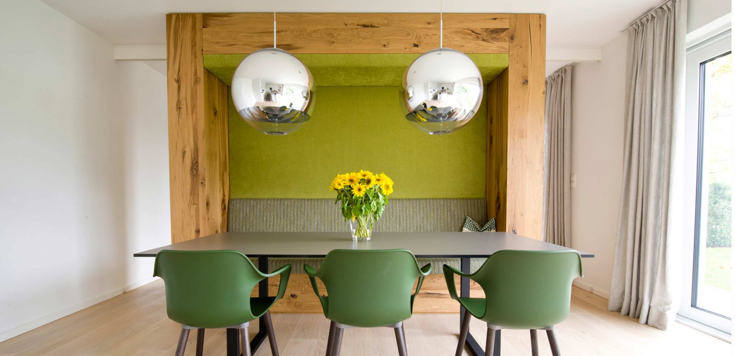 Blick auf den Essbereich mit waldgrünen Akzenten und Einbaumöbel mit Sitznische in der Villa 