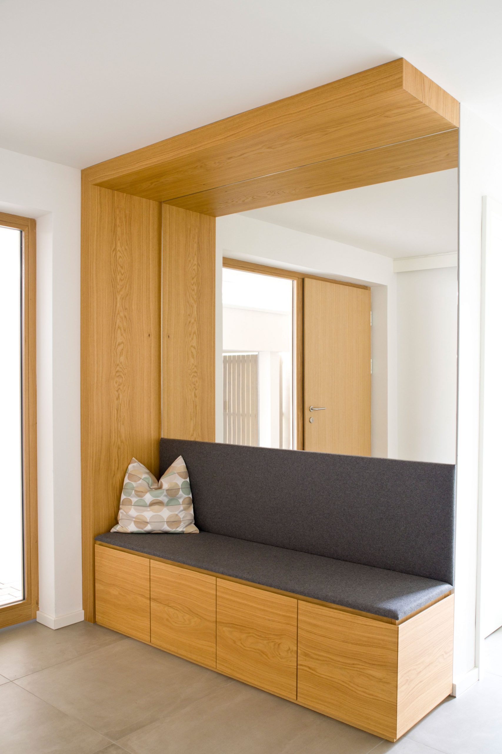 Das multifunktionale Sitzmöbel im Eingangsbereich mit passgenauer Spiegelwand.