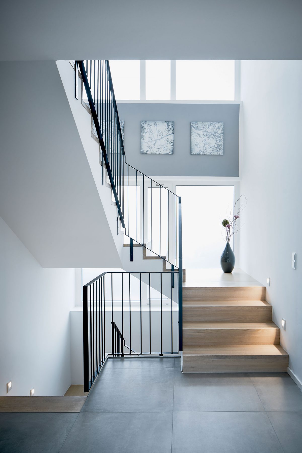 Die sanierte Treppe in der Villa BYR mit neuen Tritt- und Setzstufen aus Holz und neuem Geländer sowie eine abschnittsweise LED Wandeinbauleuchten.